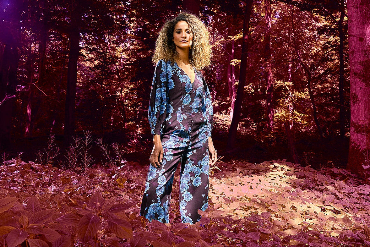 Woman in a floral jumper standing in a forest with a purple hue