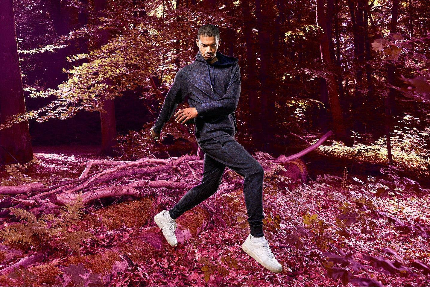 Person running through a forest wearing a paisley hoodie and matching jogger.